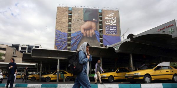 epa12899724 Iranians walk past a large-scale billboard referring to the Strait of Hormuz and reading in Persian, “Forever on Iran’s hand,” in a square in Tehran, Iran, 19 April 2026. Tensions between the United States and Iran continue as the Strait of Hormuz remains blocked.  EPA/ABEDIN TAHERKENAREH