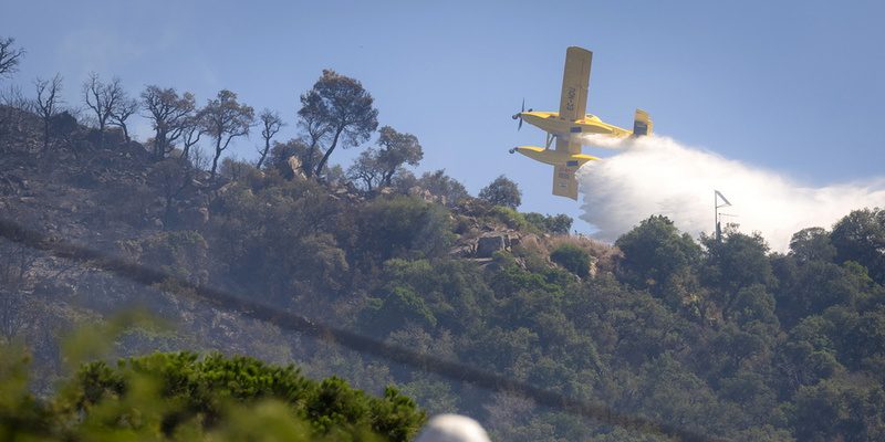 epaselect epa13085309 A firefighting plane drops water over a forest fire spreading to a residential area in Calonge, Catalonia, Spain, 04 July 2026. A wildfire that broke out in the municipality of La Bisbal d'Emporda is rapidly spreading, prompting authorities to order the lockdown of residents and tourists in Calonge and other nearby municipalities.  EPA/DAVID BORRAT